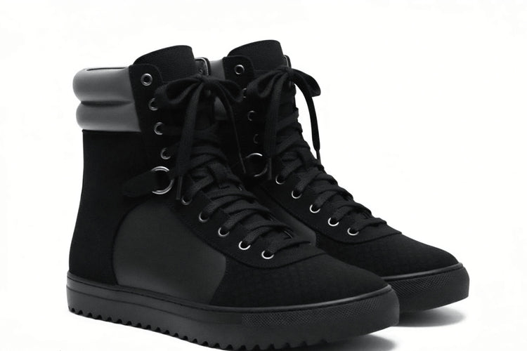 A pair of black high-top sneakers with black laces, black soles, and a gray collar accent, shown on a white background.